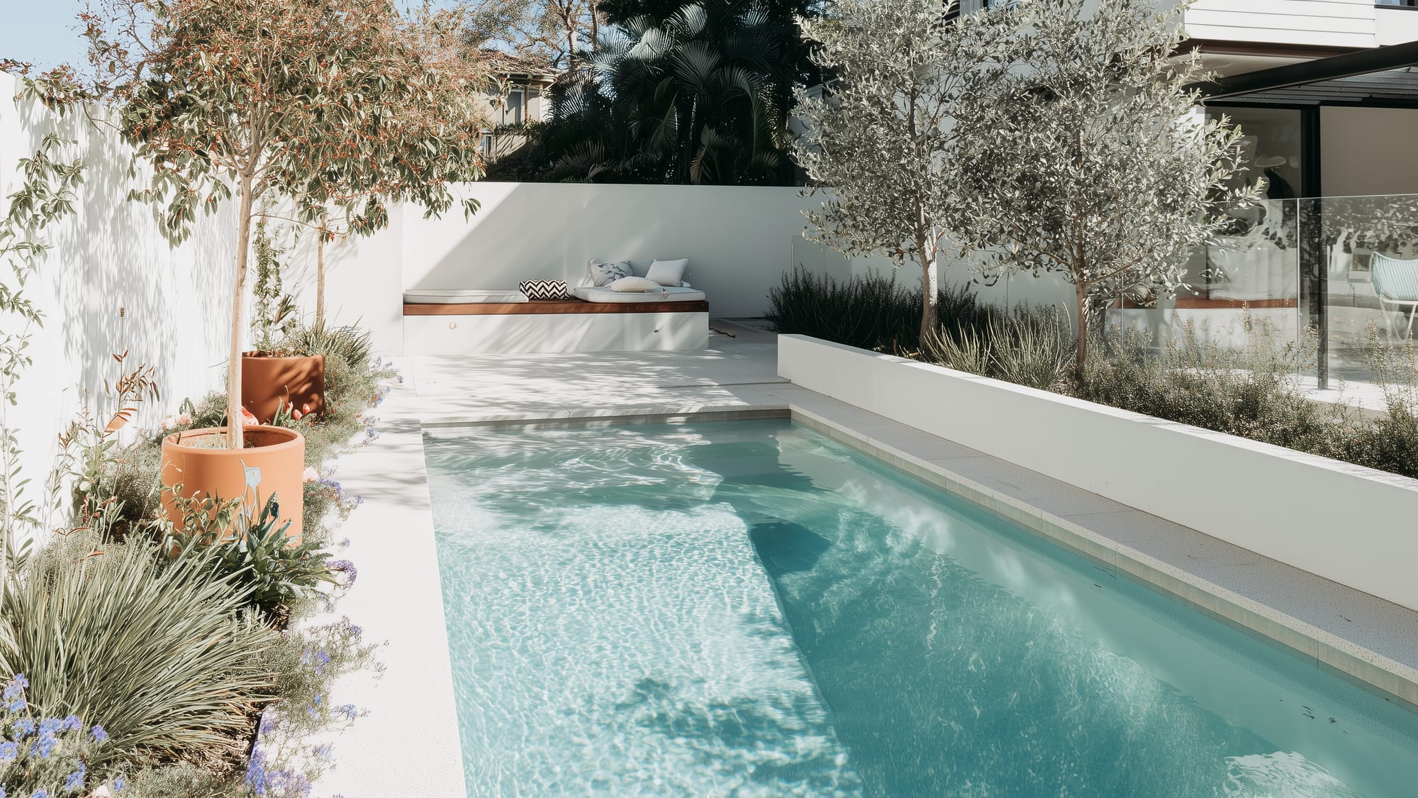 A calm, considered Australian backyard pool with rendered walls and mature planting