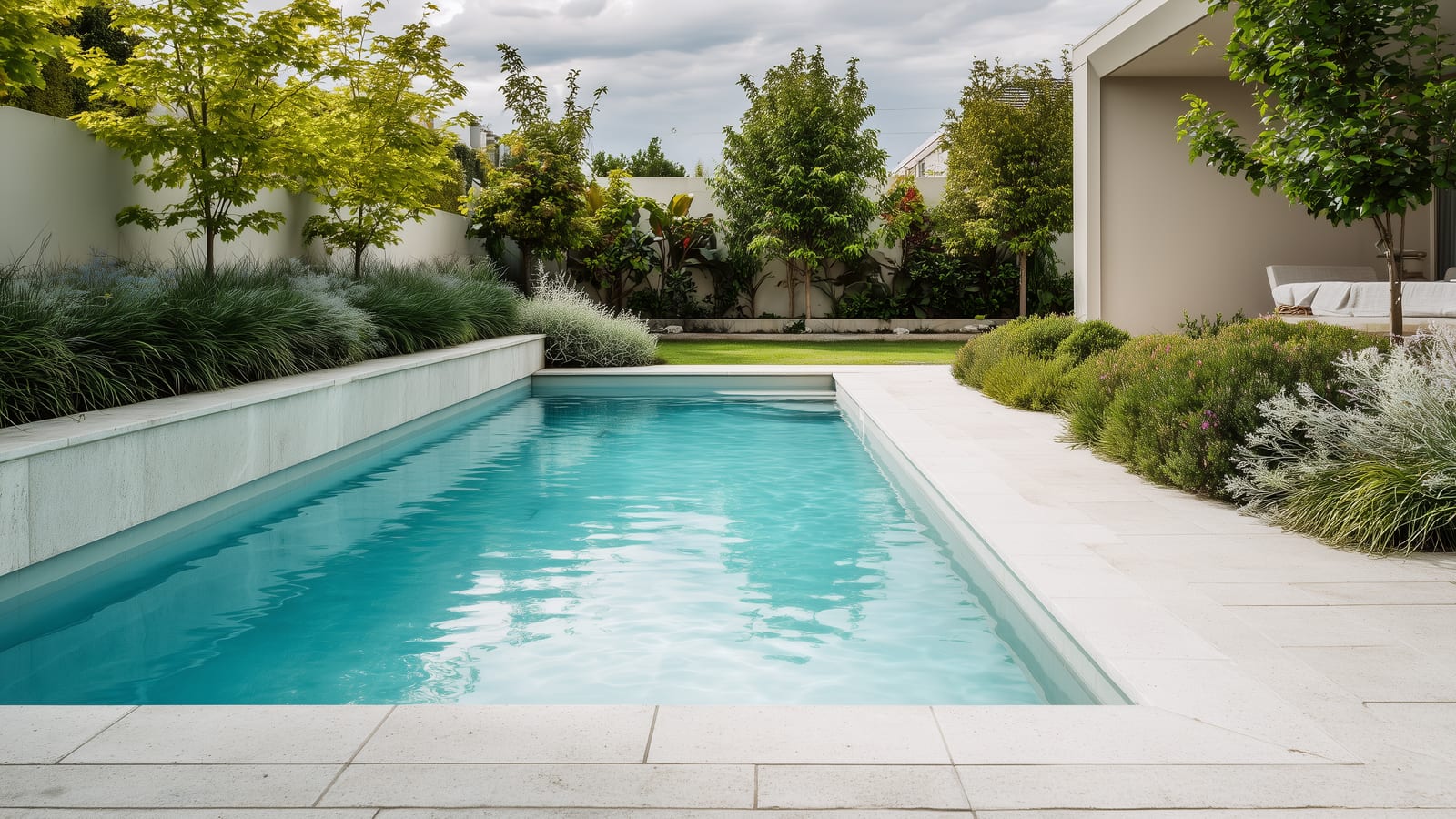 Smooth pre-formed fibreglass pool with soft rounded edges bordered by ornamental grasses